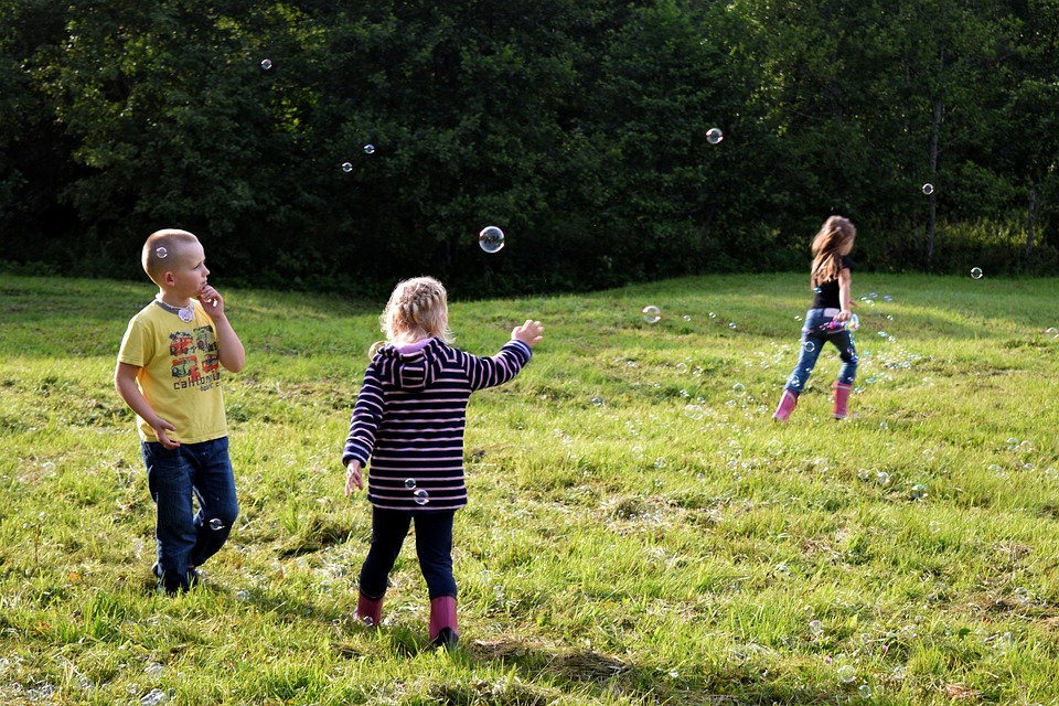 Children engage in phsyical play by chasing bubbles