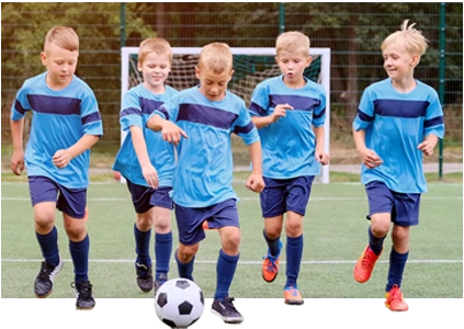 Cinco niños con camisa azul corriendo con la pelota.