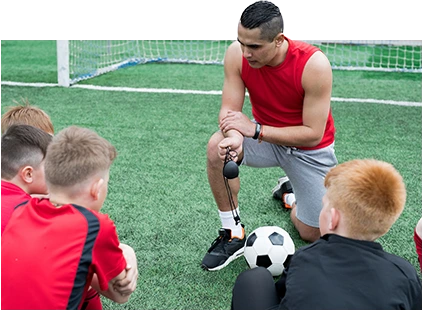 Entrenador enseñando a los niños a jugar al fútbol.